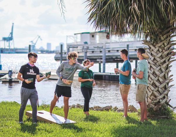 Students playing corn hole on the riverfront.